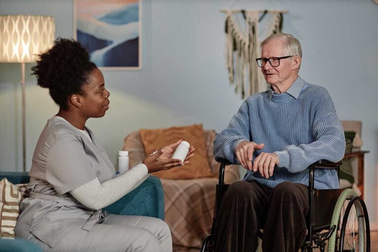 A group of seniors socializing in a bright common room with comfortable seating and large windows.