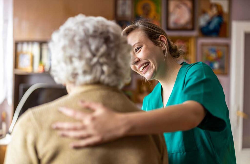 A senior resident sitting and talking with a caregiver at a table filled with paperwork and informational brochures.