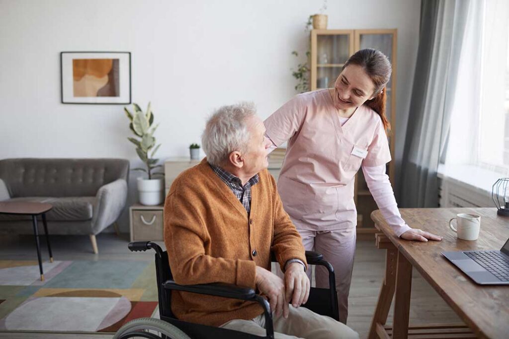 Family member sits with an older adult in a comfortable room, looking at photos together.